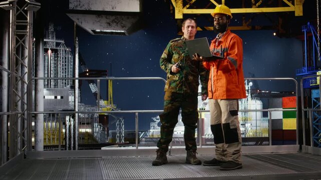 Military personnel on offshore vessel speak through walkie talkie to coordinate escort duty and safeguard oil extraction infrastructure against terrorist threats and coastal risks. Camera A.
