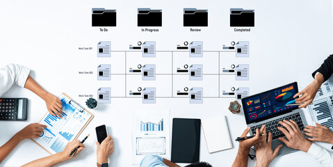 A top view of a business team collaborating on project management tasks. Various charts and reports are displayed, showcasing workflow, progress, and efficiency in modern offices. Trope