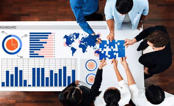 A diverse team collaborates on data analysis using a modern dashboard while assembling puzzle pieces, symbolizing teamwork and strategy in a professional office setting. Axiom
