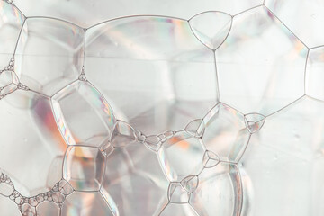 White foam bubbles shimmer with iridescent lights, creating a mesmerizing cosmetics texture in macro view.Macro Shot of Soap Bubbles Surface.Sparkling foam bubbles texture.
