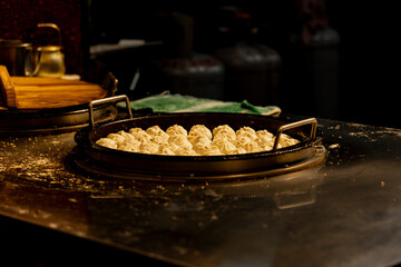 the critical moment of Shui Jian Bao (Pan-Fried Buns) being cooked on a large skillet