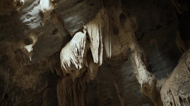 atural limestone cave texture with stalactites and stalagmites in darkness. Mysterious underground tunnel in Thailand.	
