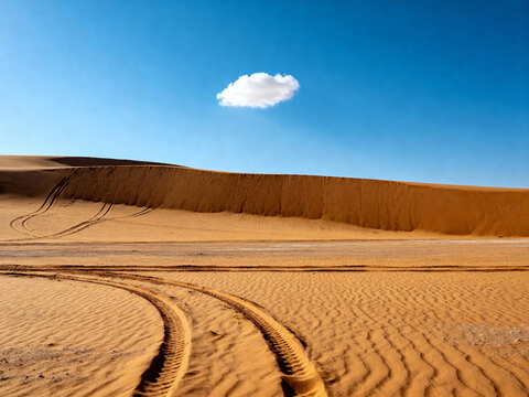 one small cloud floating over the top of an empty desert with sand dunes and tire tracks, against a blue sky.