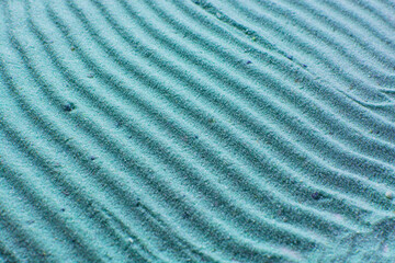close up view of textured blue sand background, beautiful sand texture, overhead view of zen pattern drawn in blue sand, Top view of fine grain texture