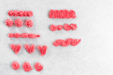 overhead view of Pink buttercream piped using a nozzle, buttercream piped using a small piping tip on a white countertop