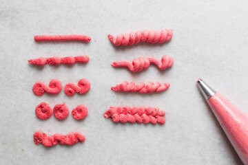 overhead view of Pink buttercream piped using a nozzle, buttercream piped using a small piping tip on a white countertop