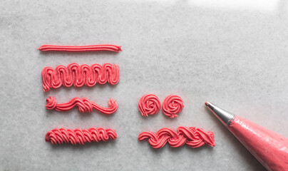 overhead view of Pink buttercream piped using a nozzle, buttercream piped using a small piping tip on a white countertop