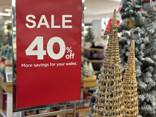 A red Sale 40 percentage off sign displayed in a retail store amidst Christmas decorations, highlighting holiday shopping deals and seasonal discounts.