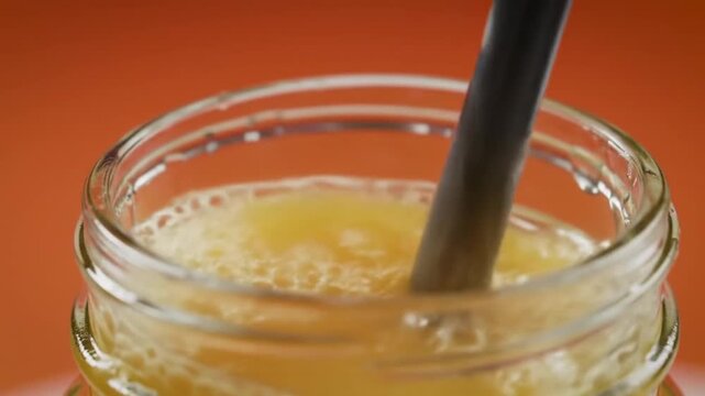 Freshly squeezed juice being poured into a mason jar with a straw for a refreshing drink