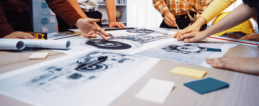 A dynamic planning session taking place in a modern office, featuring collaboration among diverse professionals analyzing blueprints, documents, and visual aids on a table. SACTR - Powered by Adobe
