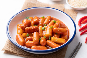 Tteokbokki (simmered rice cake) and sausage with spicy sauce in bowl on white background, Korean food
