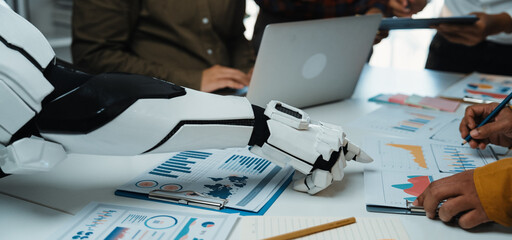 A robotic arm interacts with human colleagues in a dynamic office setting, analyzing data and brainstorming innovative strategies on a contemporary workspace.Noogenesis