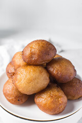 close up view of nigerian puff-puff on a white plate, nigerian fried dough balls, homemade bofrot on a white background