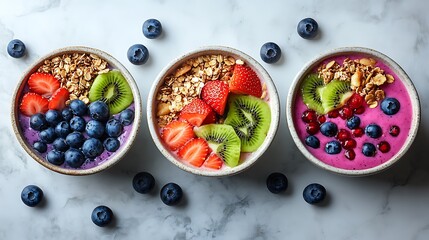 Delicious smoothie bowls topped with vibrant fruit and granola, perfect for a healthy breakfast or snack on a bright marble surface, a colorful and tasty treat