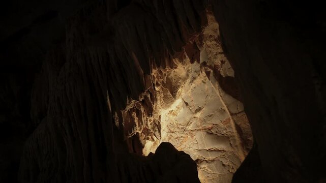 atural limestone cave texture with stalactites and stalagmites in darkness. Mysterious underground tunnel in Thailand.	
