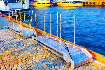 Obraz premium Aluminum gangways, which are also known as access bridges or passarella, connecting paved dock to the water. Structures provide safe and stable access for people to board or disembark from boats