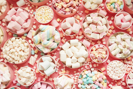 Confectionery and sweeties varieties background: light pink and white marshmallows, sugar confetti and candies, selective focus