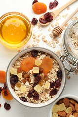 Making granola. Oat flakes, dried fruits and other ingredients on white table, flat lay