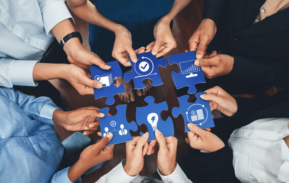 A vibrant display of hands from diverse individuals assembling puzzle pieces representing business solutions, symbolizing teamwork and collaborative strategy in a modern office setting. Amity - Powered by Adobe