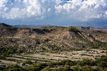 Tabernas desert landscape featuring eroded arid hills under a cloudy blue sky in Andalusia, Spain