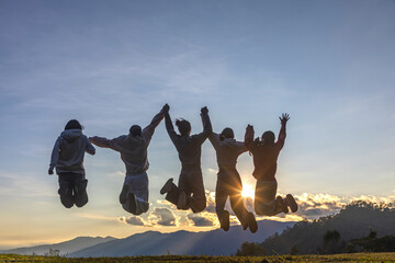 Five friends happy jumping at the sunset on mountain to welcome the New Year.