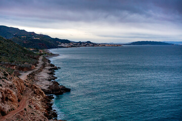 Mojacar coastline with tranquil sea meeting rugged shore at sunset following a path in Spain