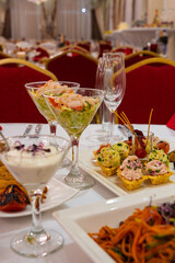 Vilnius, Lithuania - May 9 2025 - A formal dinner setting with various appetizers and shrimp cocktails served on a table with red chairs in the background.