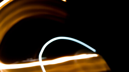 Brightly colored lines of light extend in rapid motion across the dark asphalt, creating a dramatic...