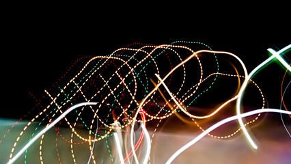 Brightly colored lines of light extend in rapid motion across the dark asphalt, creating a dramatic...