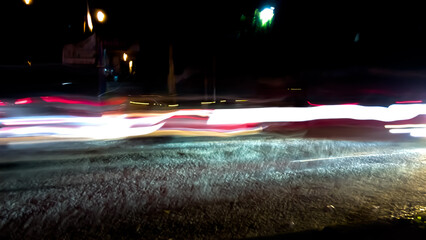 Brightly colored lines of light extend in rapid motion across the dark asphalt, creating a dramatic...