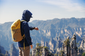 Successful backpacker checking the smart watch hiking in mountains