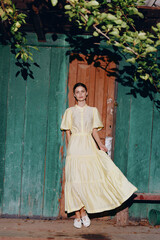 Fototapeta premium woman dress vintage doorway authenticity inclusivity, yellow maxi dress portrait leaning against green wooden door in warm sunlight