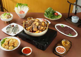 Traditional hot pot lamb stew with fresh vegetables and noodles on portable burner for communal dining