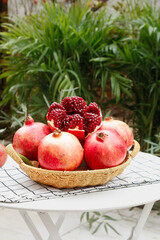 Fresh Pomegranate Fruit with Red Seeds in Wicker Basket on Garden Table