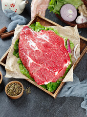 Raw beef brisket cut with fresh vegetables and cooking ingredients in rustic wooden presentation box