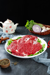 Raw Beef Steaks with Fresh Herbs and Cooking Ingredients on Dark Background