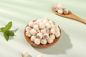 Dried lotus seeds with removed hearts in wooden bowl on white background