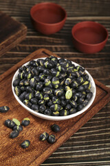 Fresh black beans with green sprouts in white bowl on wooden board - healthy legume ingredient