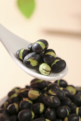 Crispy Salt Roasted Black Beans with Green Spice Coating on White Spoon - Healthy Protein Snack
