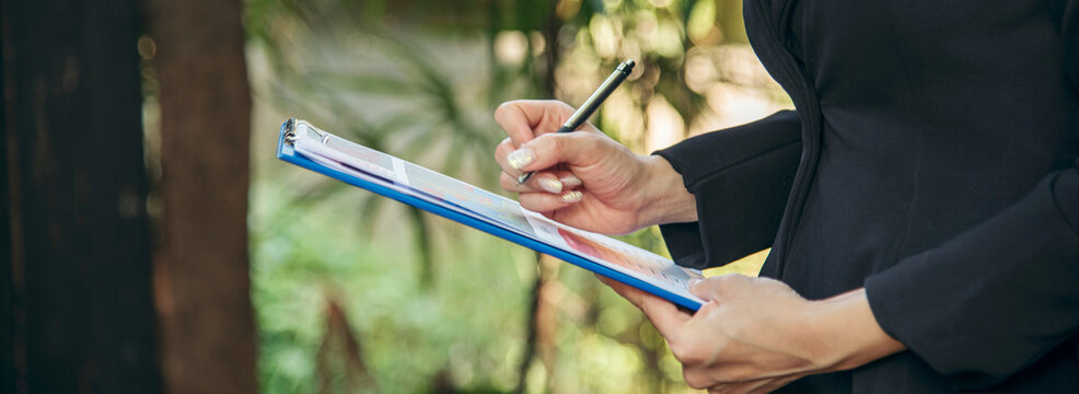 Banner Man hands writing notebook diary with coffee cup and smartphone on wood desk. Banner Close up man hands use pen sitting wood table. Men write planner note diary office agenda with copy space - Powered by Adobe