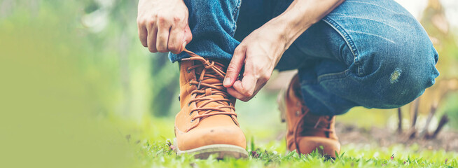 Banner man kneel down tie shoes lace on industry worker boots. Close up shot of man hands tied...