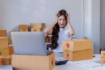 Fototapeta premium Business woman young postal worker is suffering from a headache and is sitting at her desk full of packages 