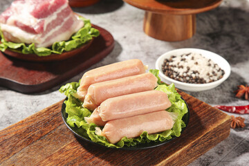 Raw Sausages and Bacon with Spices Ready for Barbecue Grilling on Wooden Cutting Board