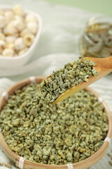 Dried Green Tea Granules with Lotus Leaf in Wooden Spoon - Natural Herbal Tea Ingredients