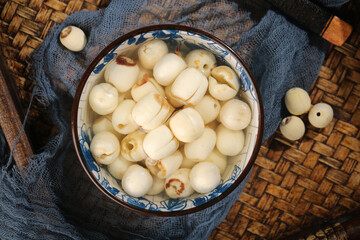 Dried lotus seeds in ceramic bowl - healthy Asian superfood ingredients on bamboo mat