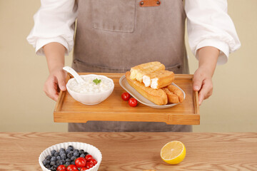 Chef Serving Delicious Breakfast Combo with Corn Fritters and Soup on Wooden Tray