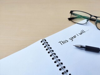 New year 2026 resolution concept. This year i will written on a notebook with wooden table background. Copy space
