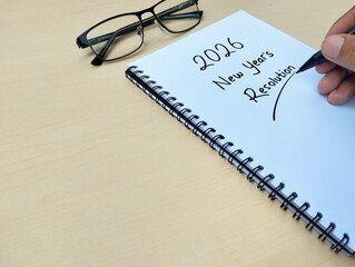 New year 2026 resolution concept written on a notebook with wooden table background. Copy space