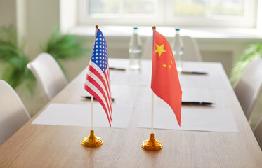 Flags of China and America against table in conference room. Bilateral political relations and...