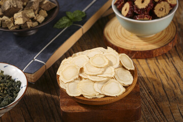 Traditional Chinese Medicine Ginseng Slices and Herbal Health Products on Wooden Background
